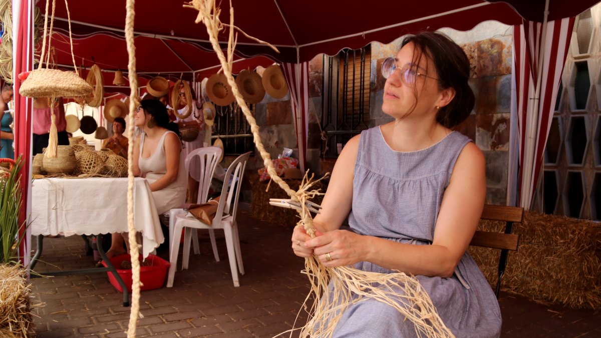 Una artesana treballa un trenat a la seva parada de la Fira de Mas de Barberans