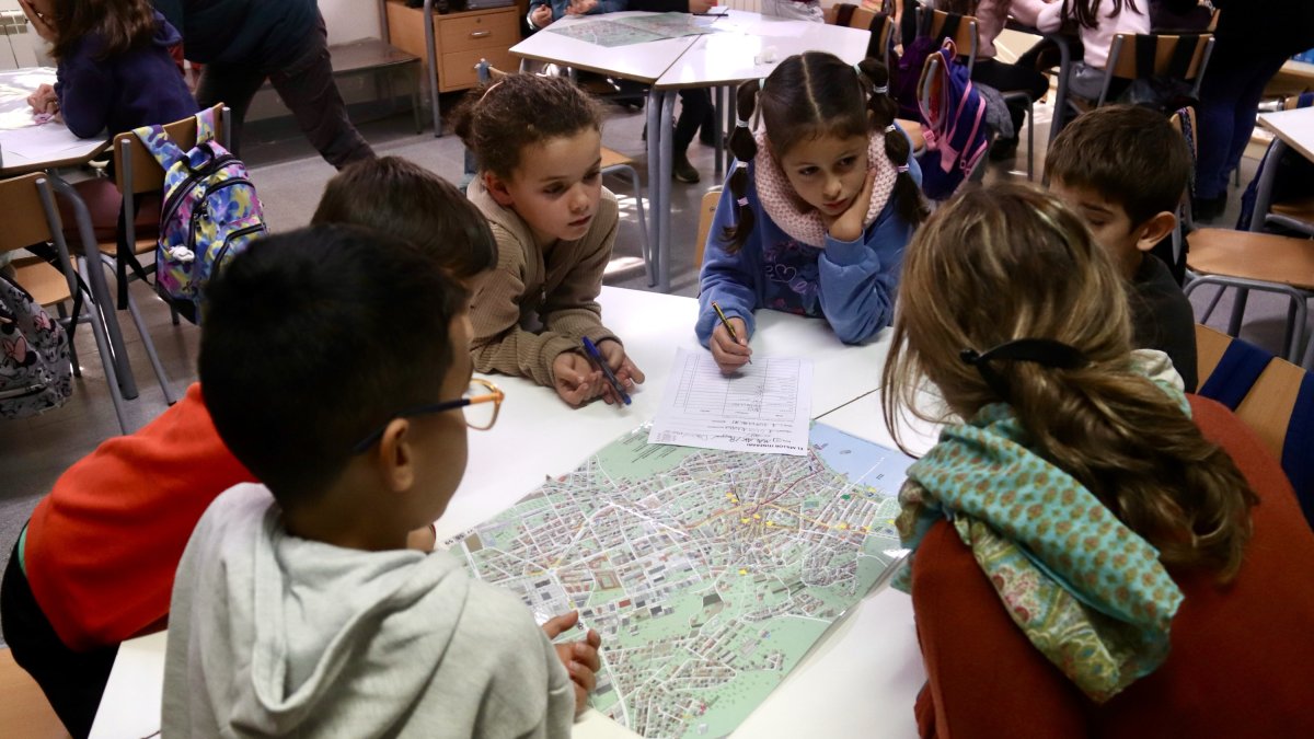 Imatge d'arxiu d'un grup d'alumnes de l'escola de la Draga que miren en el mapa com crear un itinerari per fer amb la classe