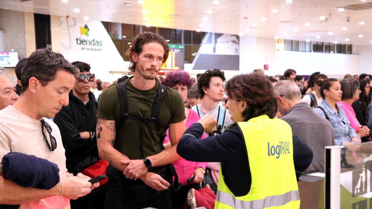 Fotografia d’arxiu de viatgers a l’estació de Sants consultant informació