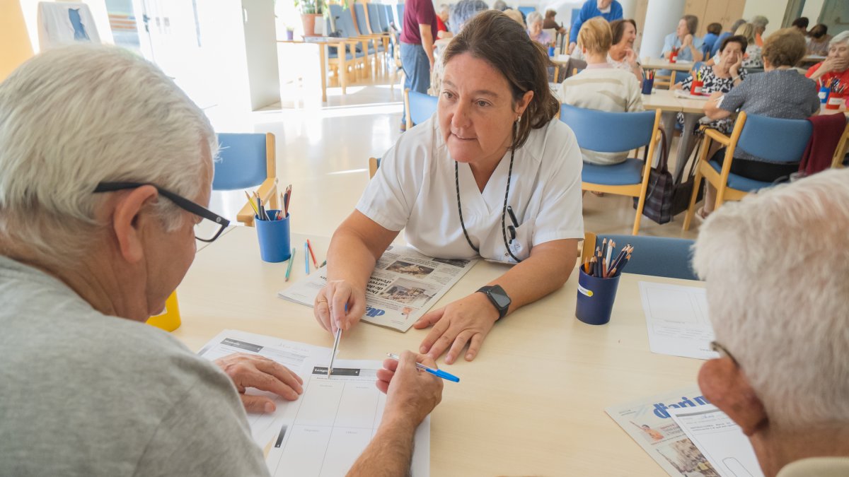 Una membre de l’equip tècnic del programa d’estimulació cognitiva de l’Hospital de Dia Francolí atén a dos usuaris.