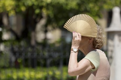 Una mujer se protege del sol con un abanico.