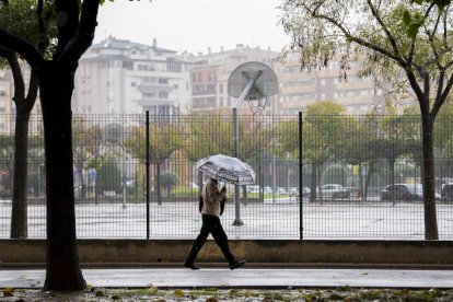 Una persona pasea este lunes bajo la lluvia en Castellón.