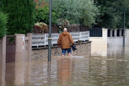 Un home caminant per un carrer inundat de la urbanització La Móra de Tarragona.