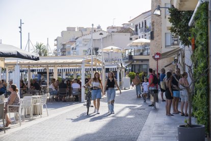 Turistas caminando y comiendo en el paseo de Miramar de Cambrils el verano del 2023.