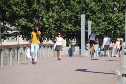 Vianants caminant per Lleida durant el primer dia d'onada de calor.