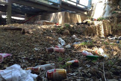 En un lateral de les escales s'acumulen peces de roba i desenes de llaunes i ampolles d'alcohol.