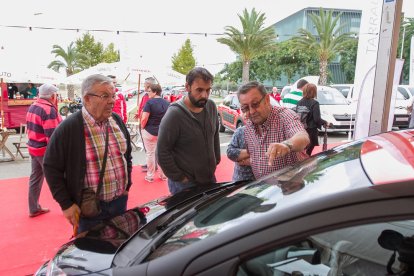 Visitantes en la feria en un stand de automóviles.