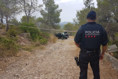 Un agent de Mossos d'Esquadra, amb el cotxe del detingut al fons.