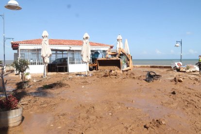 Pla obert d'un carrer de les Cases d'Alcanar, amb una màquina netejant el fang.