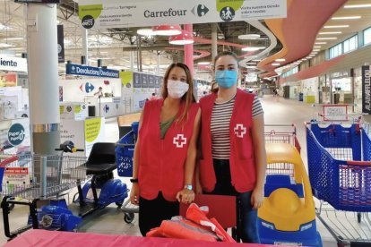 Dos voluntarias recogiendo material escolar en el Carrefour de les Gavarres.