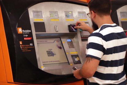 Un noi utilitzant una màquina d'autovenda de Rodalies.