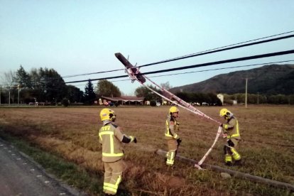 Els Bombers treballant en un pal de la llum caigut pel vent a la Vall d'en Bas.