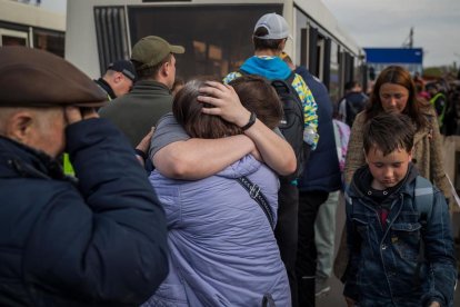 Refugiados se abrazan tras llegar al estacionamiento de un centro comercial en Zaporiyia.