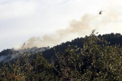 Un helicóptero bombardero sobrevolando el incendio declarado en una parcela de les Borges del Camp.