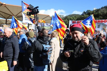 Plano medio de un manifestante tomando un vermú con la frontera en el fondo.