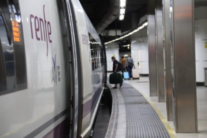 Una persona entrando en un tren AVE en la estación de Sants de Barcelona.