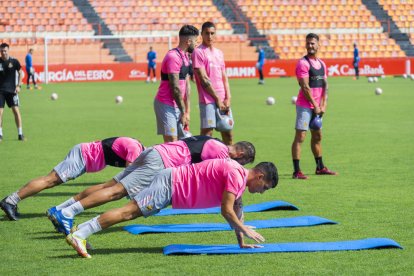 Jugadors del Nàstic, entre ells Andy Escudero, fan exercicis d'estirament en l'entrenament d'ahir.