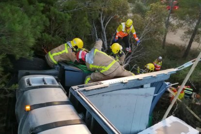 Los bomberos intentando sacar al camionero de la cabina.