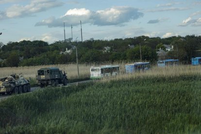 MIlitars rusos escuchan los buses que traskkades a los soldados ucranianos evacuados de la planta de Azovstal.