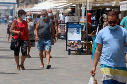 Personas paseando con mascarillas por la zona marítima de Calafell Platja, el punto más turístico del municipio.