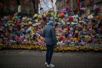 Mural con fotografías y flores conmemora a los fallecidos en la guerra en Leópolis.