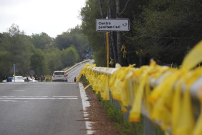 Imagen de valla de la carretera en dirección a Mas Enric adornada con lazos amarillos.