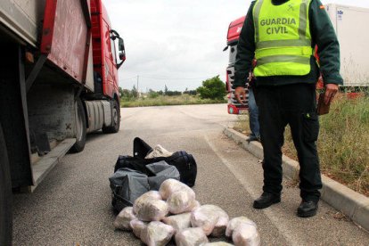 Detalle de los fardos de droga que se encontraron en el interior de un vehículo en un control custodiados por un agente de la Guardia Civil.