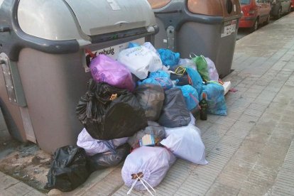 Un contenedor desbordado con la basura en la acera.