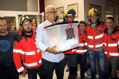 Uno de los vocales de mesa del colegio electoral del Departamento de Salud en Lleida con la urna llena de votos para el referéndum y acompañado de Bomberos, el 1 de octubre de 2017