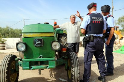 Plano general de dos agentes de los Mossos D'Esquadra conversando con un campesino al lado de su tractor en una masía de Vallmoll (Alt Camp), el 7 de julio del 2017