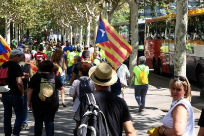 Pla general alçat de desenes de participants a la manifestació de l'ANC i Òmnium caminant `per l'avinguda Diagonal després de baixar dels autobusos.