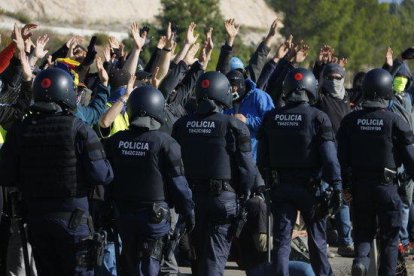 Participants del tall de l'AP-7 a Vandellòs aixequen les mans mentre agents dels antidisturbis dels Mossos d'Esquadra passen per davant d'ells.