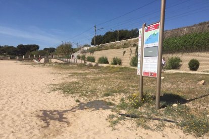 L'aigua escapa sota el cartell de platja blava.