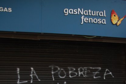 Un home passa per davant de la reixa de la seu de Gas Natural a Reus, acabada de pintar amb un grafit on s'hi llegeix 