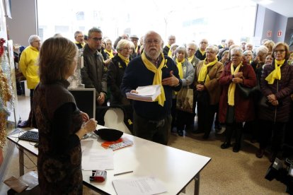 Plano medio del portavoz de los 'Avis i àvies per la llibertat' de Reus entregando las cartas de queja en la oficina del Síndic, desplazada a la capital del Baix Camp, con miembros del colectivo al fondo.