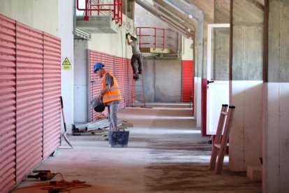 Dos treballadors, a la zona de Tribuna, realitzant els treballs previs a l'acabat de la zona.