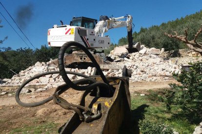 La màquina excavadora sobre les runes de la casa derruïda del matrimoni d'Alfara de Carles. Imatge del 20 de març de 2017 (horitzontal)