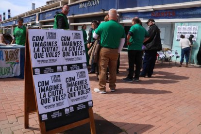 Un cartell de la jornada per imaginar un model de ciutat per Tarragona. Darrere, una parada de la PAH.