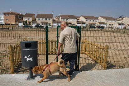 Un hombre pasea su perro en un pipican instalado en el barrio Juroca de Reus.