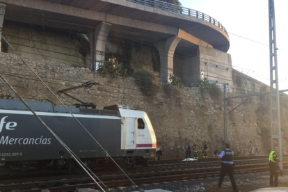 Al fons de la imatge es veu es cos de l'home, cobert, i al costat d'una màquina de tren.