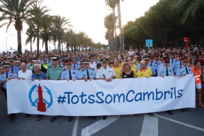 Representantes de cuerpos policiales y de servicios de emergencias sostienen una pancarta delante de miles de personas en una manifestación contra el terrorismo en Cambrils.