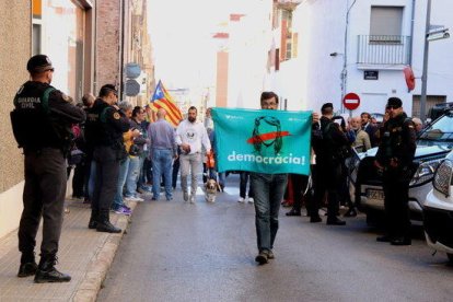 Un hombre con la pancarta 'democracia' de Òmnium Cultural durante el registro de la Guardia Civil en la empresa Unipost de Terrassa.