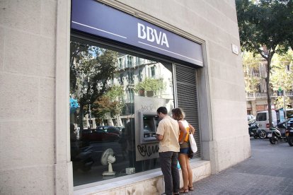 Imatge d'arxiu d'una parella davant d'un caixer automàtic del BBVA en un carrer de Barcelona.