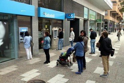 Gironins retirant diners a la sucursal que el Banc Sabadell té a Emili Grahit aquest 20 d'octubre del 2017.