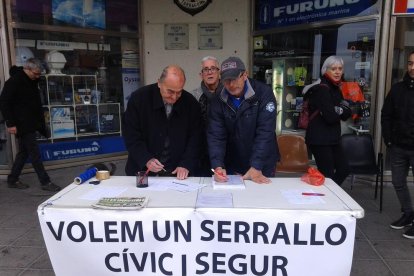 Dos veïns signen el document, a la mesa situada al raser de la Llotja del Serrallo.