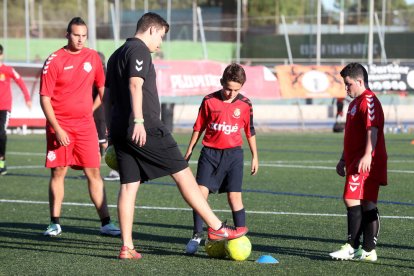 En la imagen, Carlos Rovira ayuda a los jugadores del Nàstic Genuine en aquello que necesitan. Los entrenamientos se realizan todos los lunes en el anexo de césped artificial del Nou Estadi.