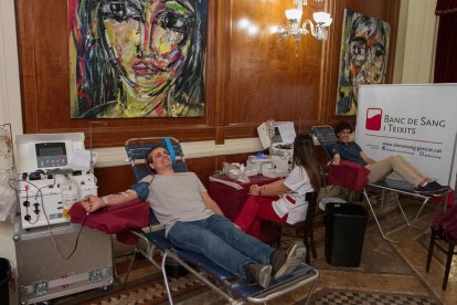 Dos dels donants de plasma a una sala del Teatre Fortuny, connectats a la màquina d'afèresi.