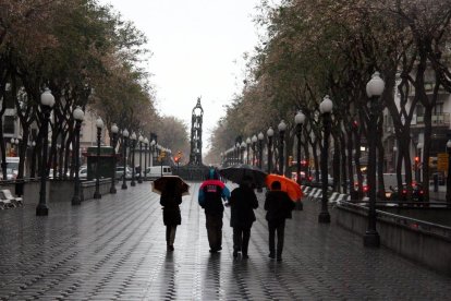 Imagen de varias personas con paraguas en la Rambla Nova.