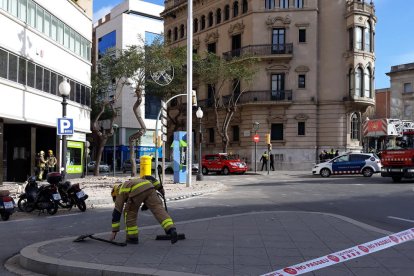 Un bomber recull restes de la terrassa que van quedar al mig del carrer després del despreniment d'ahir al matí.