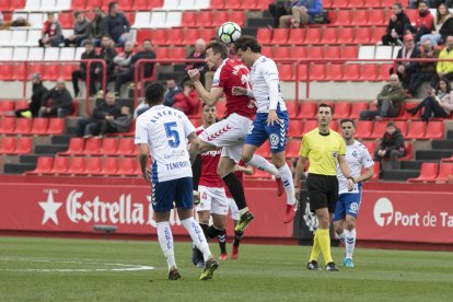 Manu Barreiro salta amb dos rivals durant el partit.